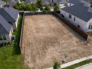 Boundary Survey stakes marking the lot line on a cleared residential rebuild site in Frisco, Texas.